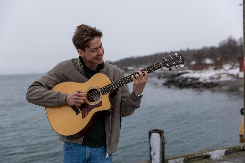 Bilde av Roger som spiller gitar nede ved havet